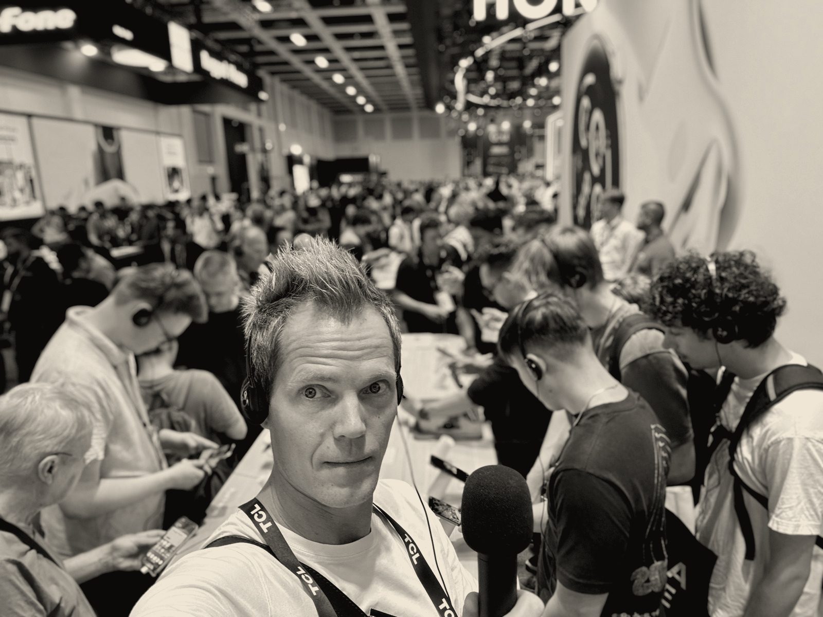 Jarle Kondrup interviewer på en teknologimesse, omgivet af besøgende med hovedtelefoner
